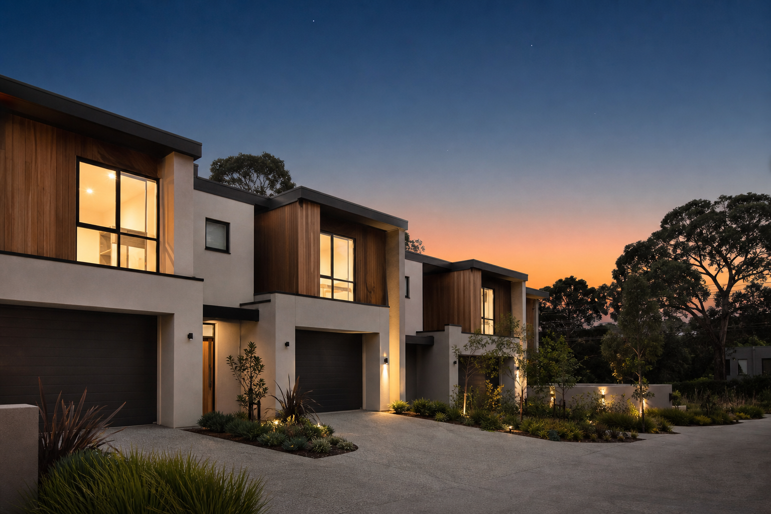 A contemporary newly-built Australian townhouse development at twilight — soft warm interior lights, fresh landscaping, deep blue-to-orange dusk sky — illustrating that new-build investment property is the policy-favoured category under the Budget 2026 reforms.